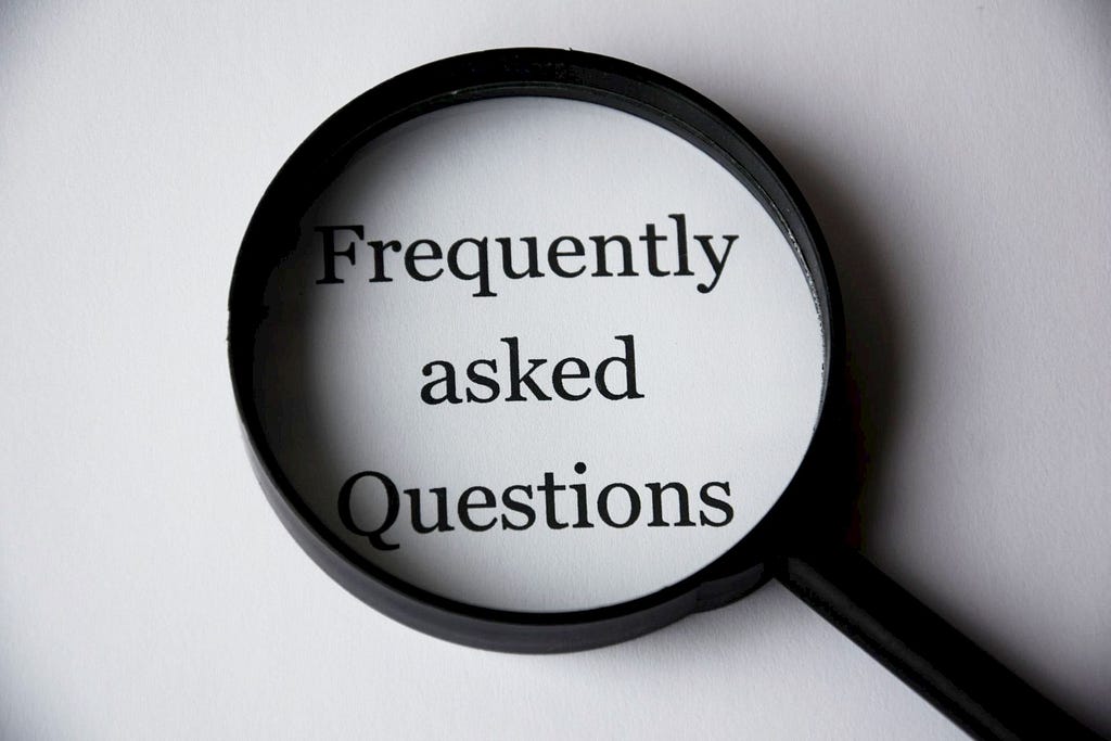 Black magnifying glass highlighting the phrase “Frequently asked Questions”