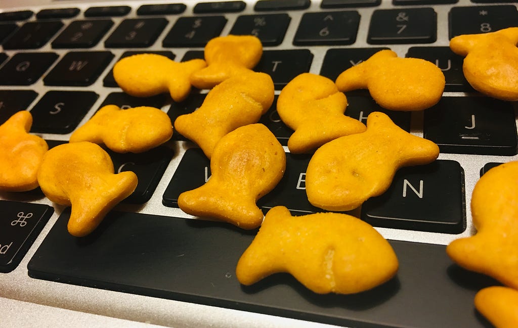 Computer keyboard strewn with goldfish crackers.