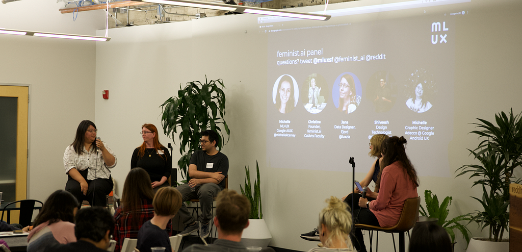 Feminist.ai panelists discussing questions on high chairs to an audience