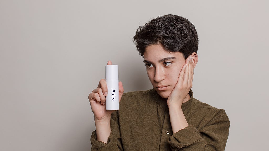 Person holding the Curology superbottle, a custom skincare formula made just for you—unlike drugstore skincare