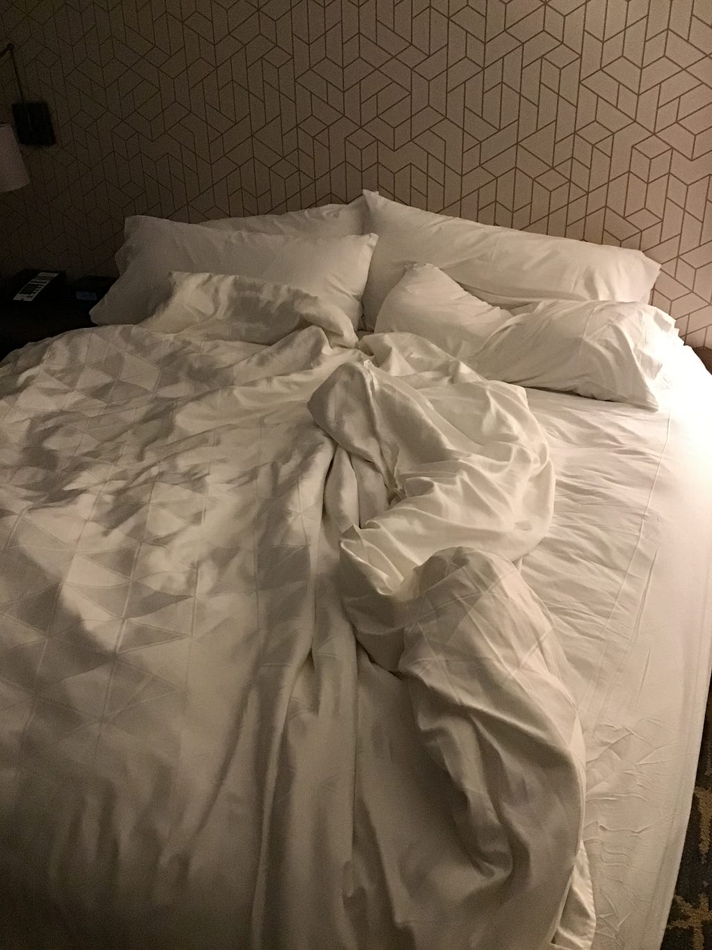 A bed with rumpled white sheets