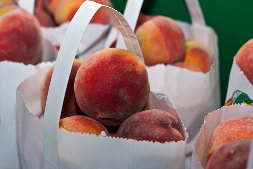 peaches in white paper bags