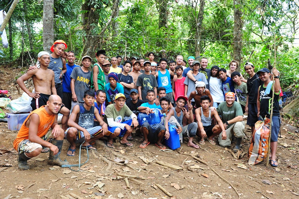A large group of people pose for a photo in the jungle.