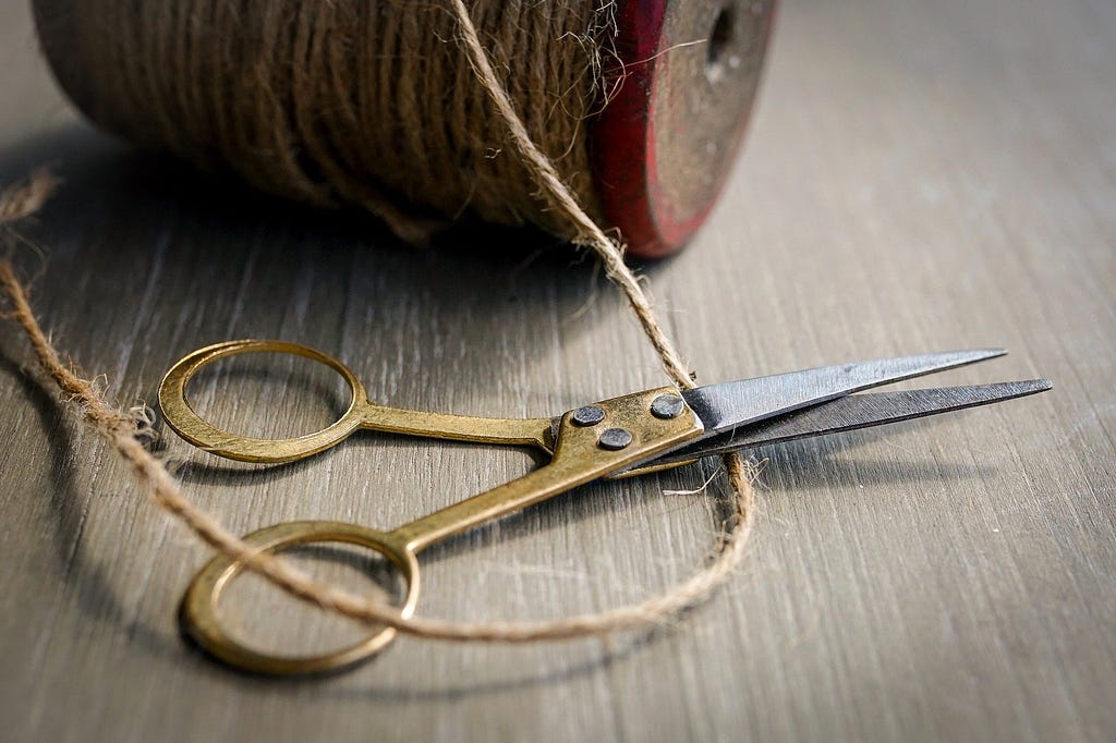 Old pair of scissors cutting hemp rope