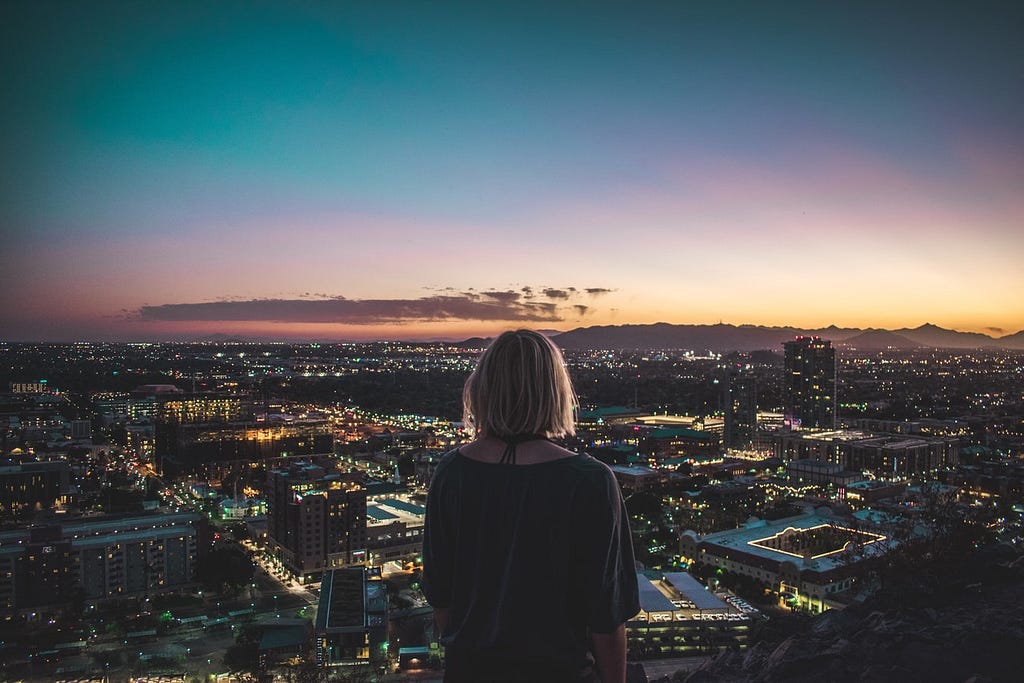 A woman looking onto the horizon of a city at sunset