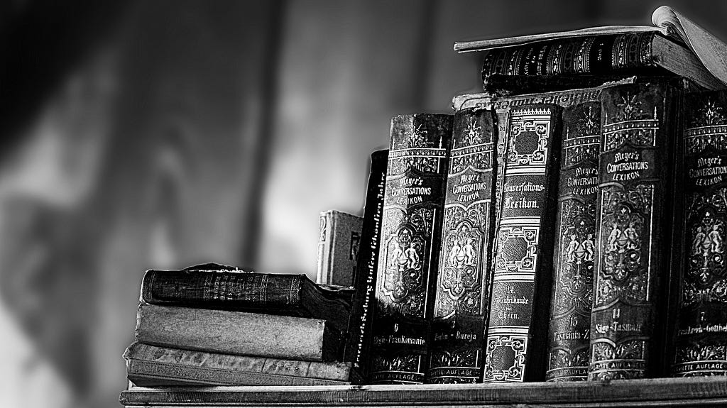 A greyscale picture of a few old books on a shelf — signifying wisdom.