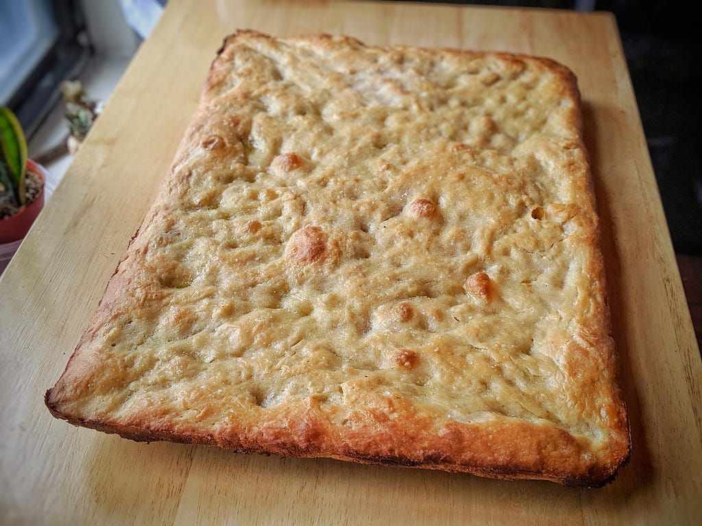 A loaf of focaccia on a wooden surface