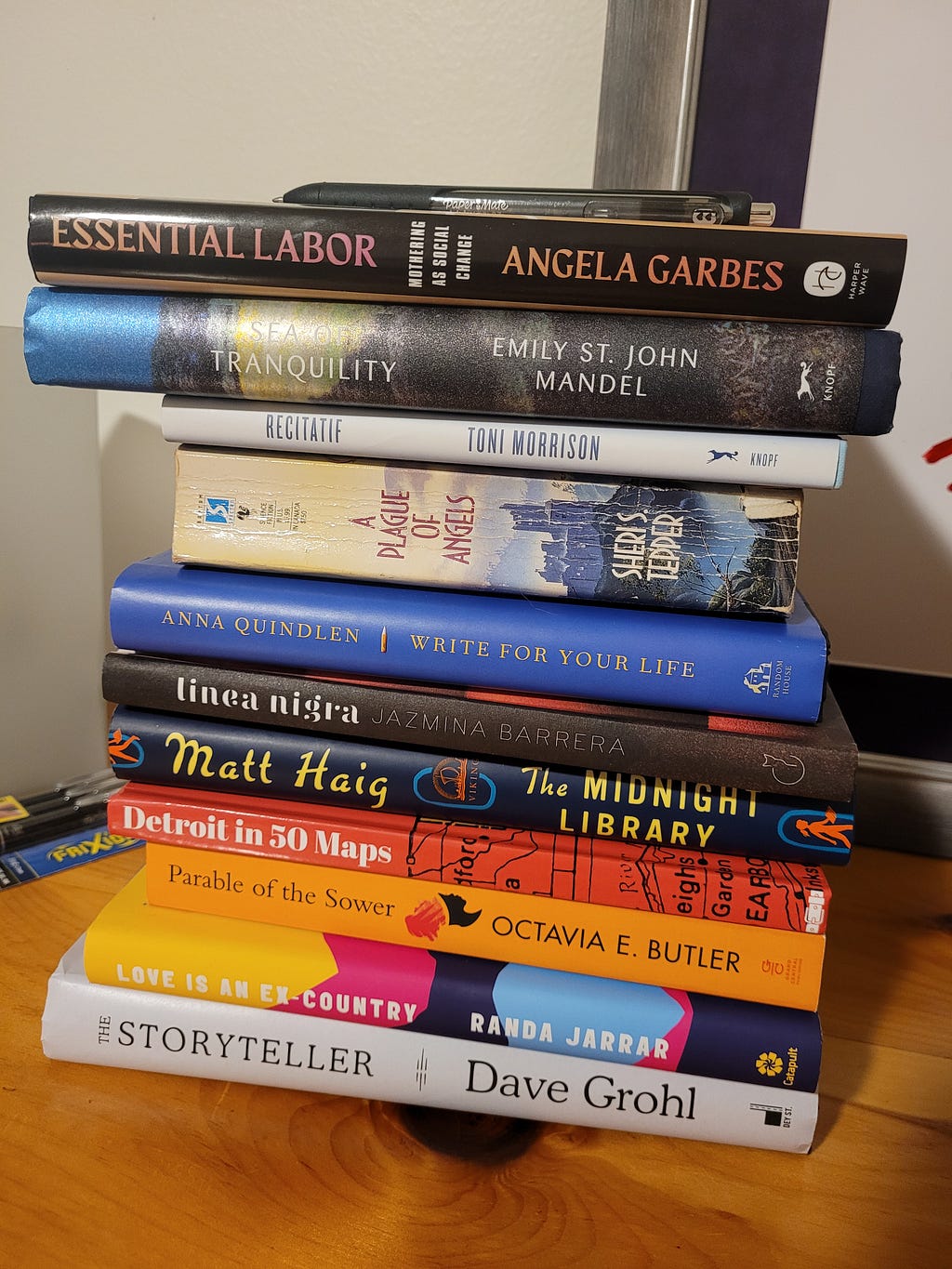 A stack of about 10 books sits on the author’s desk.