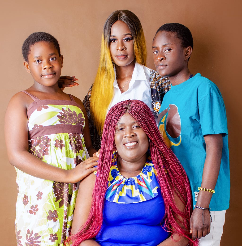 A woman and her two siblings pose for a family portrait with their mother who is seated in front of them.