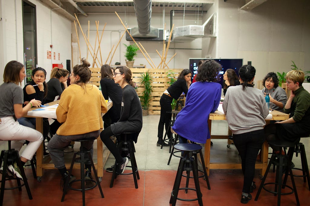 grupo de mujeres sentadas en bancos en un espacio de cowork reflexionando.