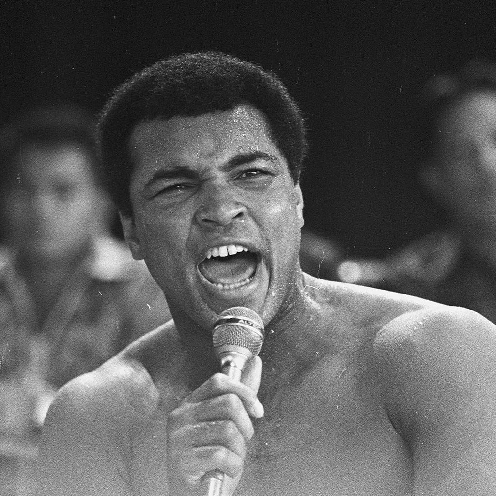 Muhammed Ali shouting into a microphone in his hand