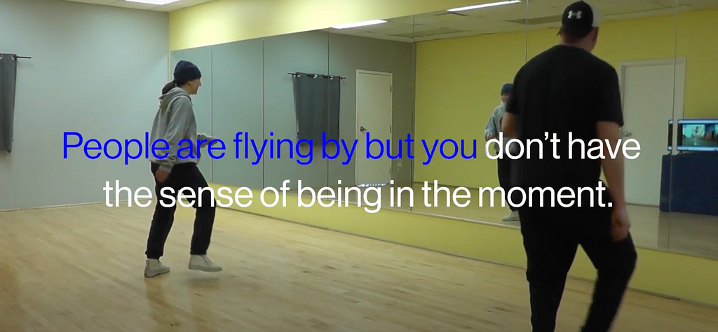 A film still with the researcher and her father in the studio with a caption from a participant interview that reads “people are flying by but you don’t have the sense of being in the moment”