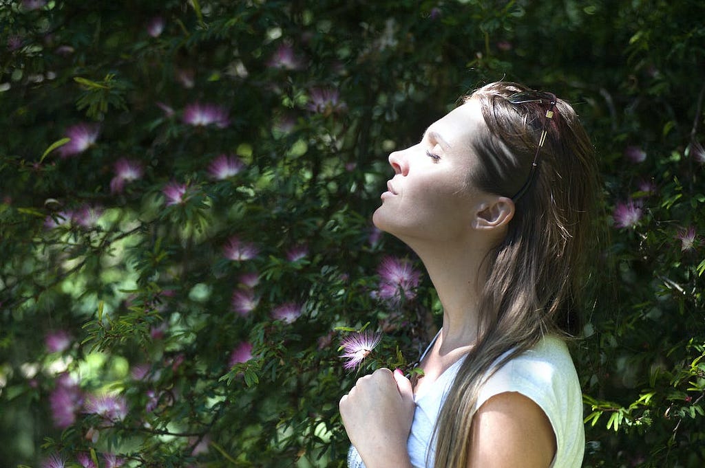 A girl in the garden breathing and feeling relaxed with eyes closed