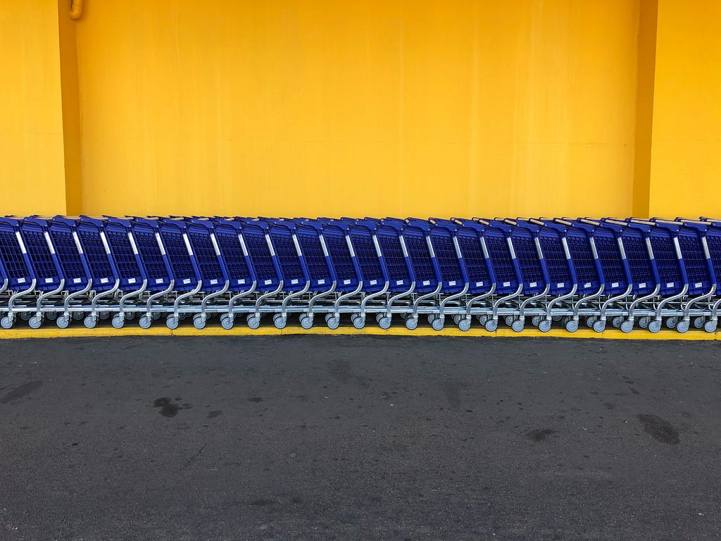 Blue carts in a row outside against a bright yellow wall.