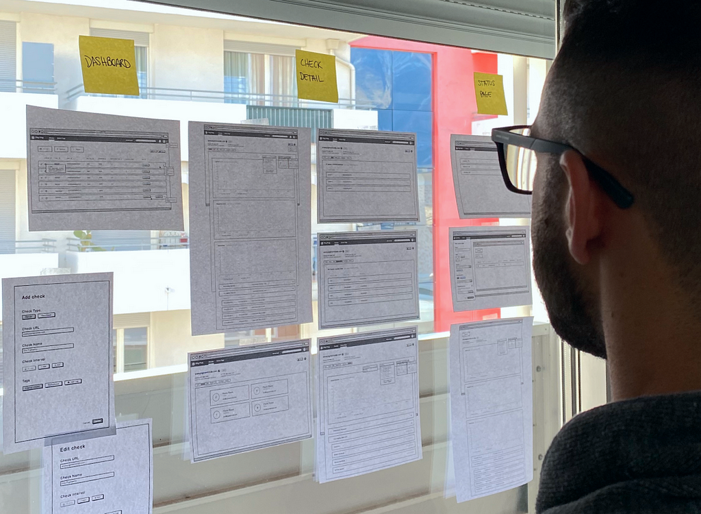 Person looking at some wireframes hanged on a large window.