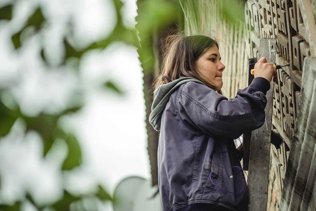 Girl restoring and carving stonewall