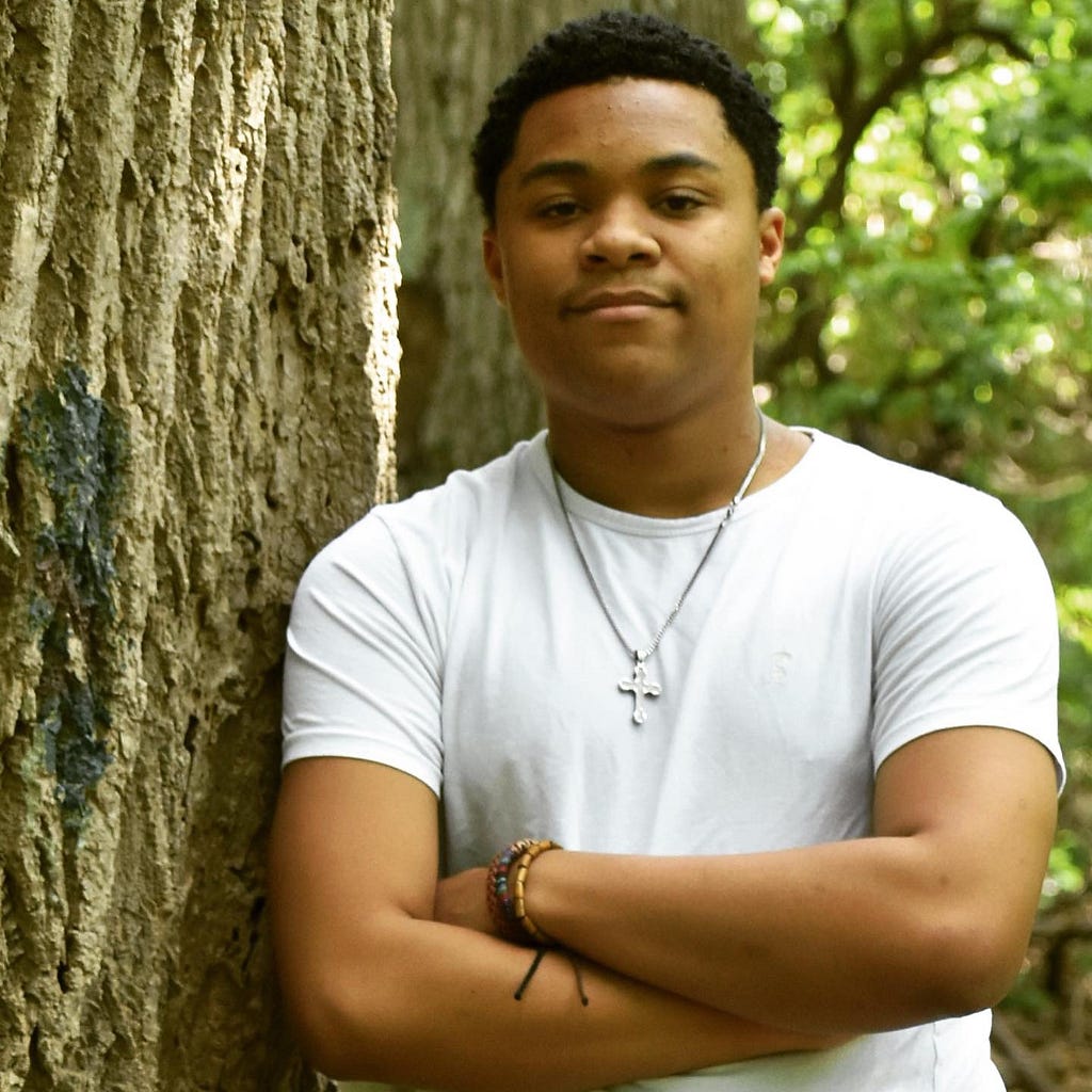 A headshot of Emmanuel Young leaning up against a tree.