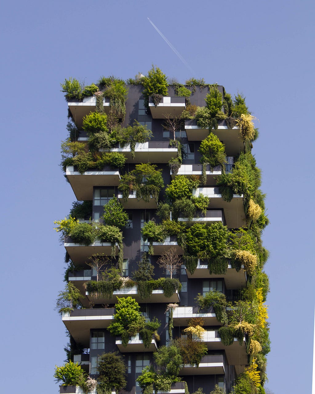Apartment building with lush vegetation hanging off of each balcony