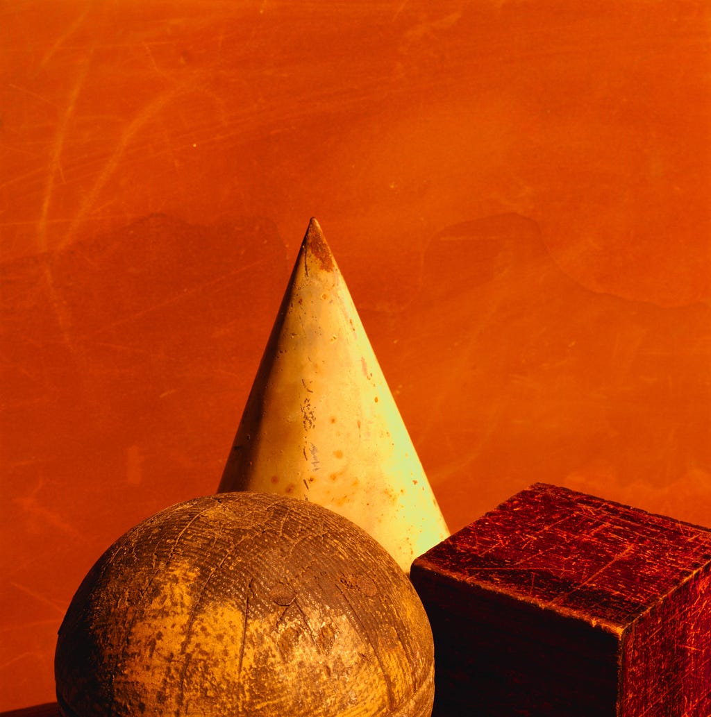 A cone, sphere and a cube in different shades between yellow and red on the orange background; Math learning can take different shapes and mistakes are part of the learning process.