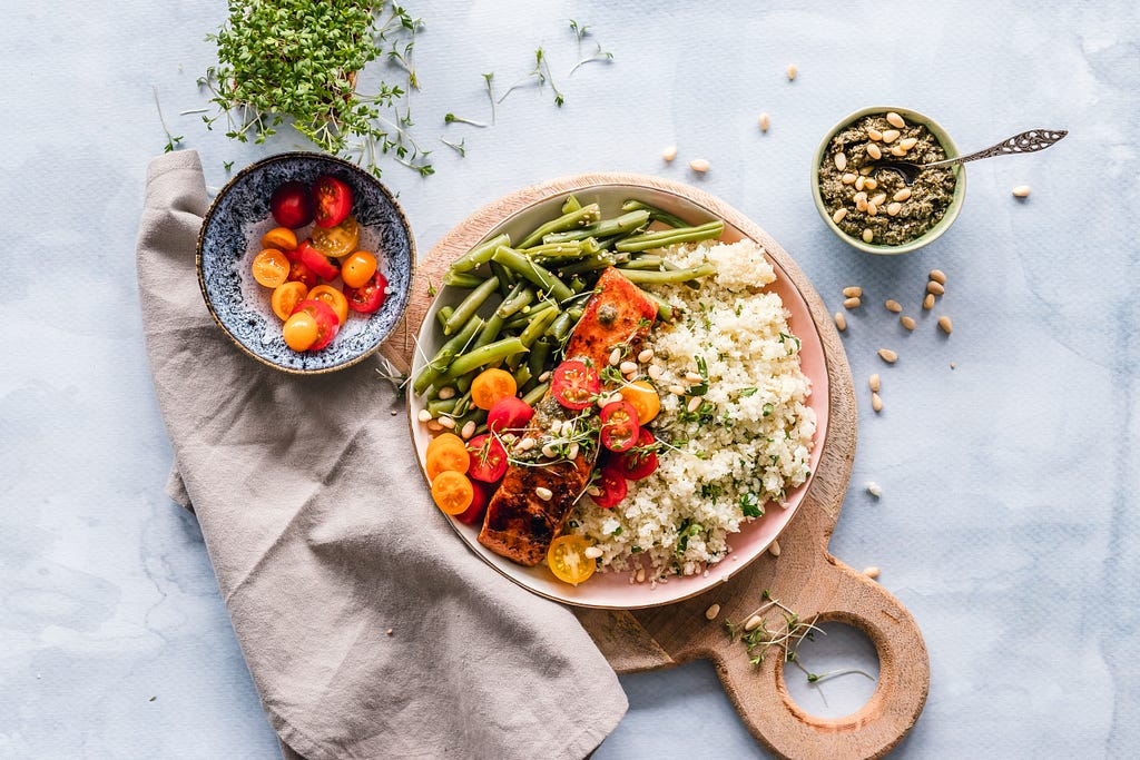 A dish with lots of different coloured vegetables and some herbs and sidedishes.