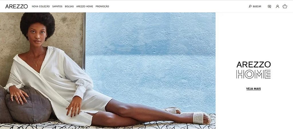 Na imagem, um recorte do e-commerce da Arezzo, onde uma mulher está em posição confortável, calçando chinelos da marca.