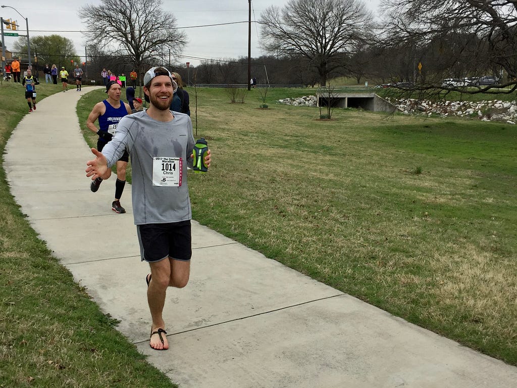 The author running a marathon in sandals and his water bottle poured all over his shirt.