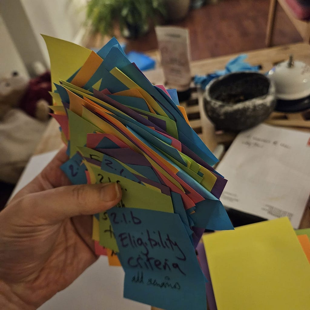 Hand full of multi-coloured postits with a cup and a notebook in the blurred background