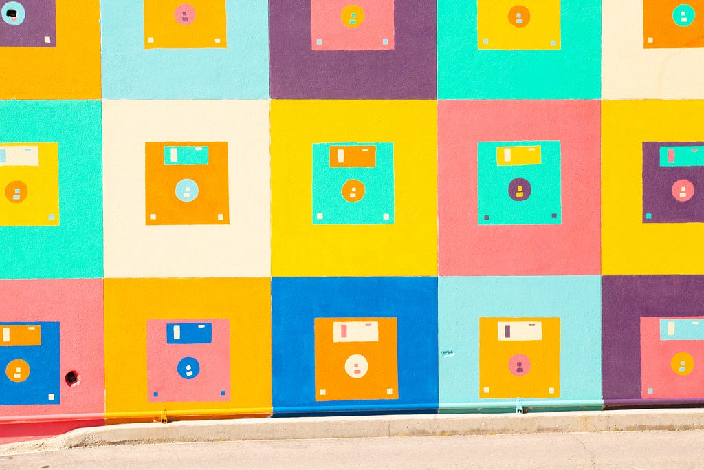 The image of a street art object. A colourful diskettes drawn on a colourful wall.