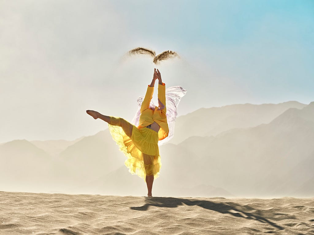 Young man in fashionable, yellow outfit dancing in desert