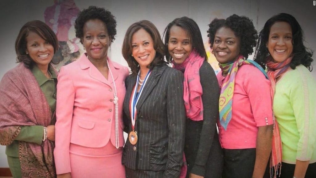 Senator Kamala Harris stands with sorority members who wear pink and green.