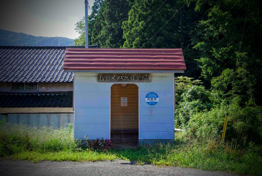 A quaint bus stop for Mt. Kyogakura complete with red roof and white walls located alongside a forest in the Ennoji region of Sakata City, Yamagata Prefecture, North Japan.