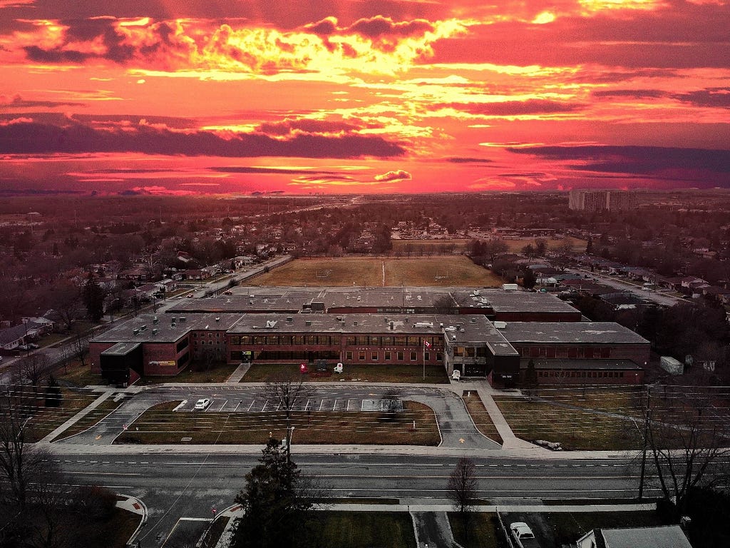 Gorgeous pink cloudy sky with a community & high school below.