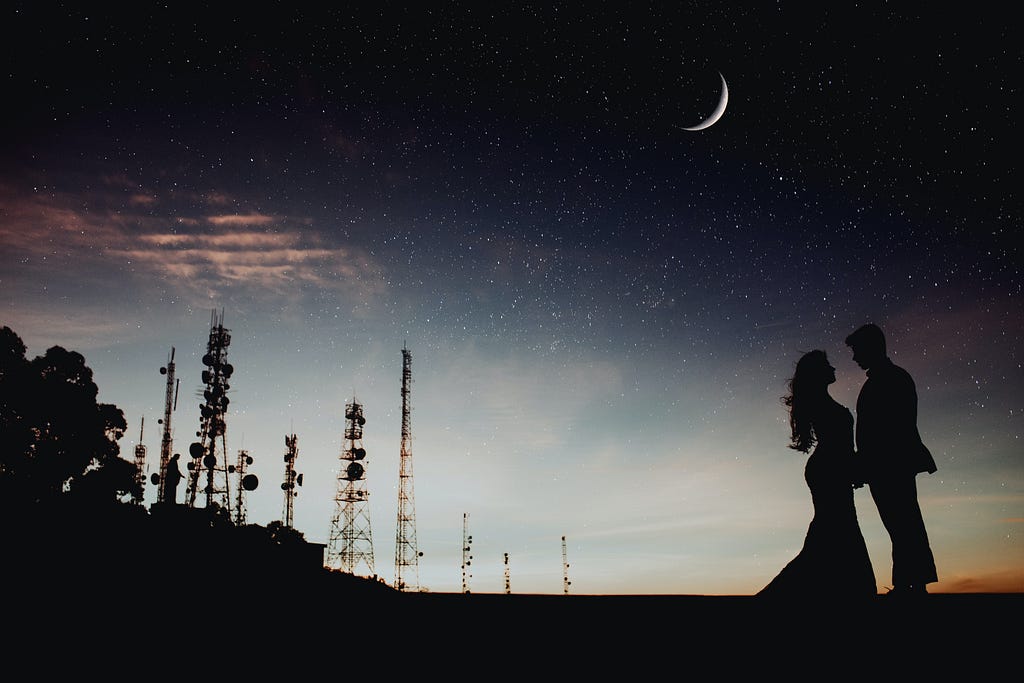 Man and woman standing outdoors under the stars.