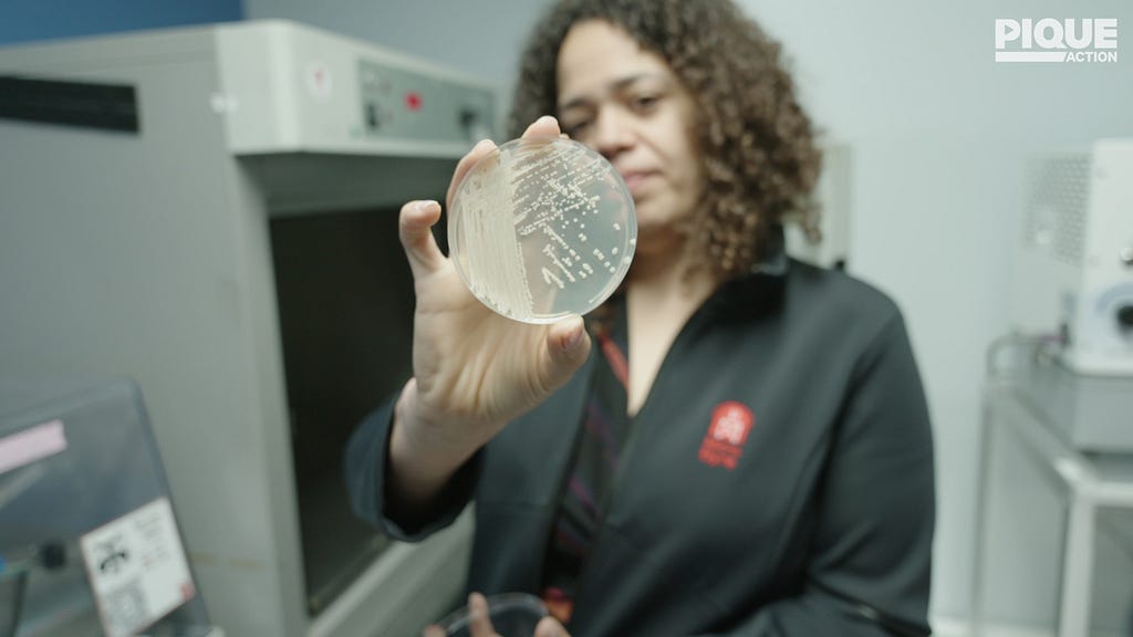 Sarah Richardson, CEO of MicroByre, holds up a petrie dish with bacterial cultures for the camera.