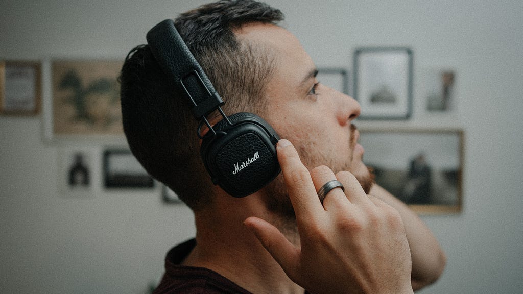 Man looking up while listening to audio on headphones.