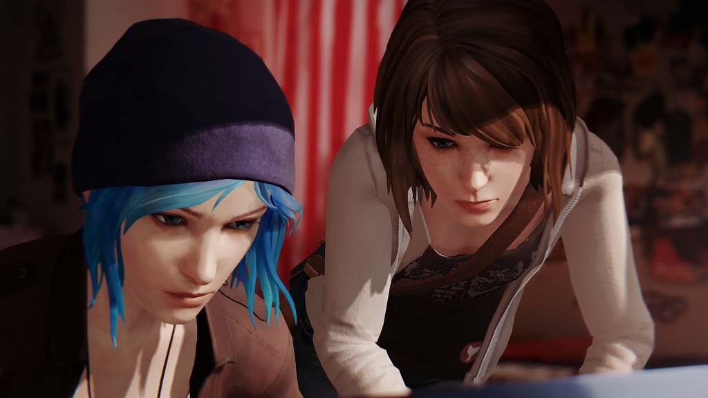 Max and Chloe looking down at something, their faces lit by sunlight. Chloe has her beanie and vibrant blue hair. Max has the strap of her satchel across her chest, a grey unzipped hoodie over her shit. There’s the blurred red and white stripes of Chloe’s American Flag hanging in the background between them.