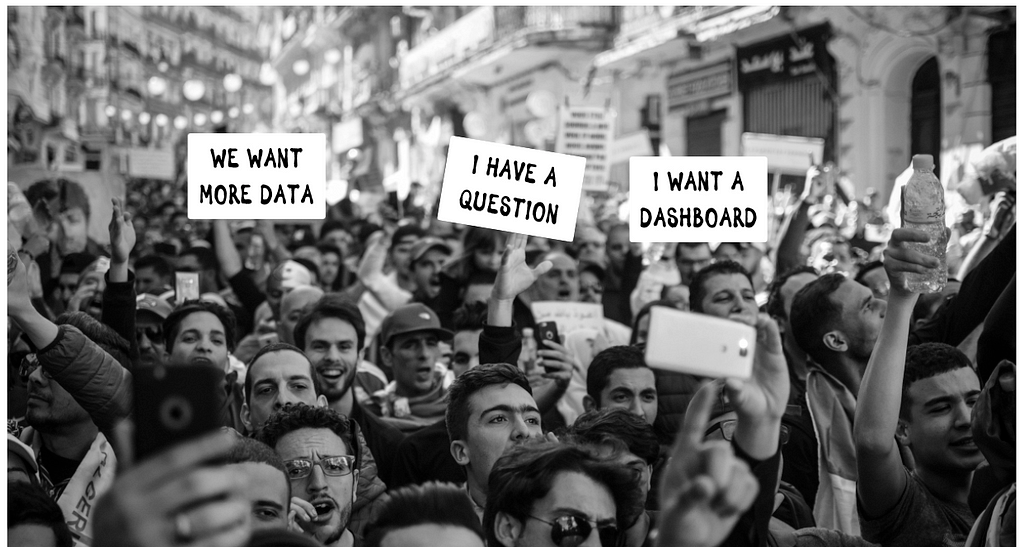 A crowd of people with protest signs like, “We want more data”, or “I have a question”