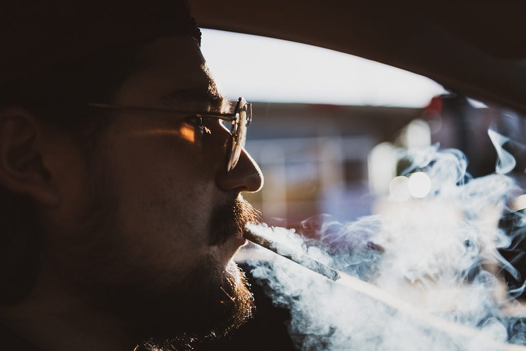 Profile of a man smoking and driving.