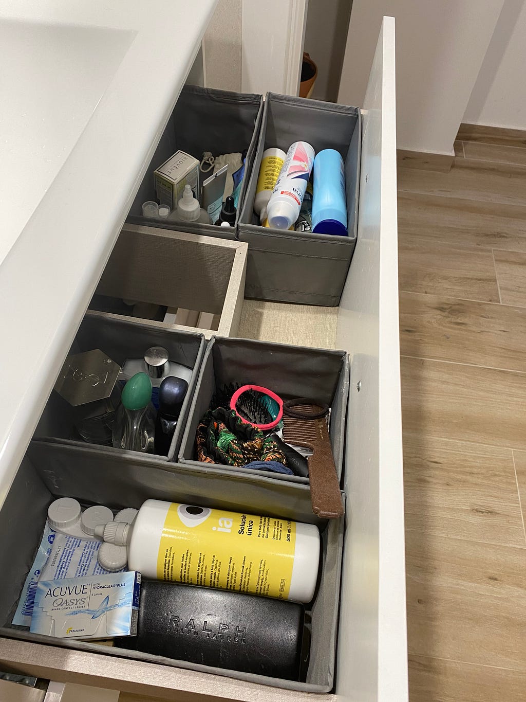 A large bathroom drawer with several small organizer boxes inside containing items that are commonly used in the bathroom