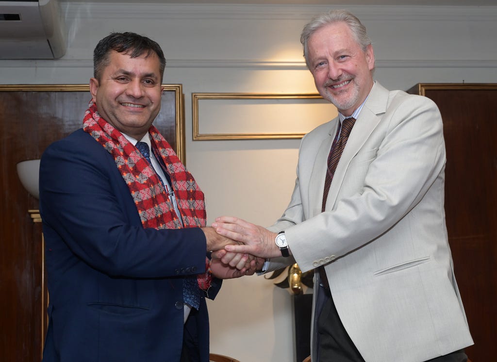 Two men shake hands and smile for the camera.