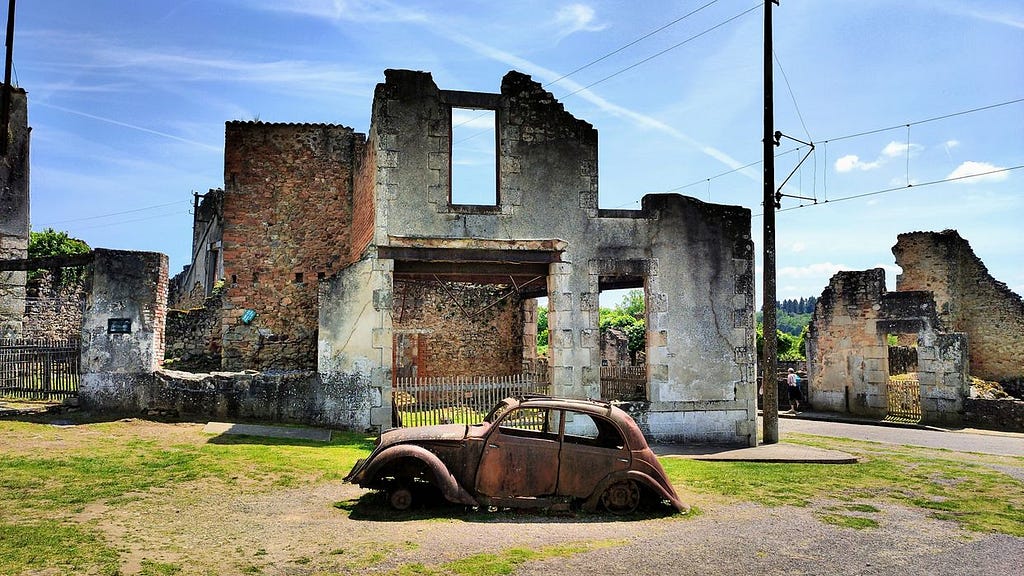A Lone Rusting Car in Front of Ruins at Oradour-sur-Glane-Photo by David Lally