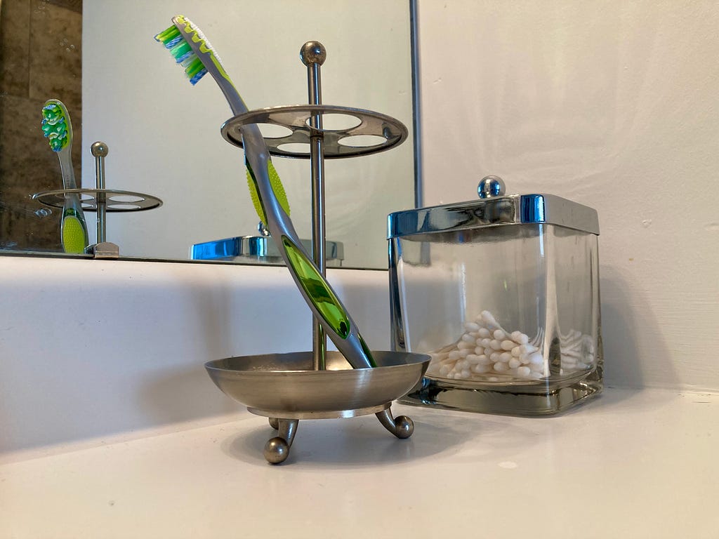 A new toothbrush in a toothbrush holder, relfected in a mirror.