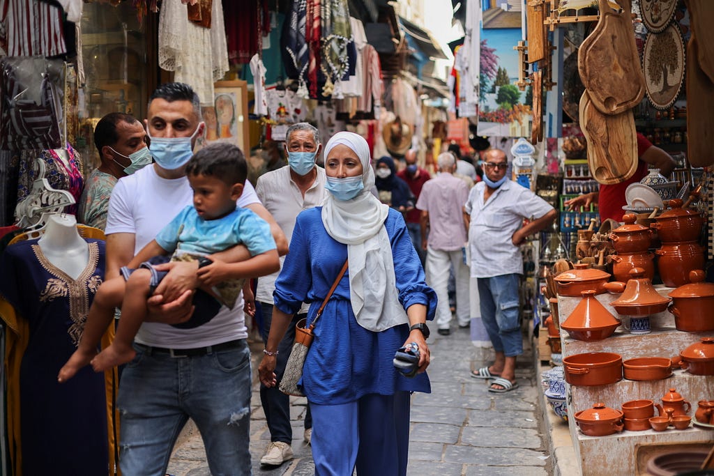 People wearing face masks walk past shops amid the COVID-19 outbreak in the Old City of Tunis, Tunisia, August 3, 2021. Photo by Ammar Awad/Reuters