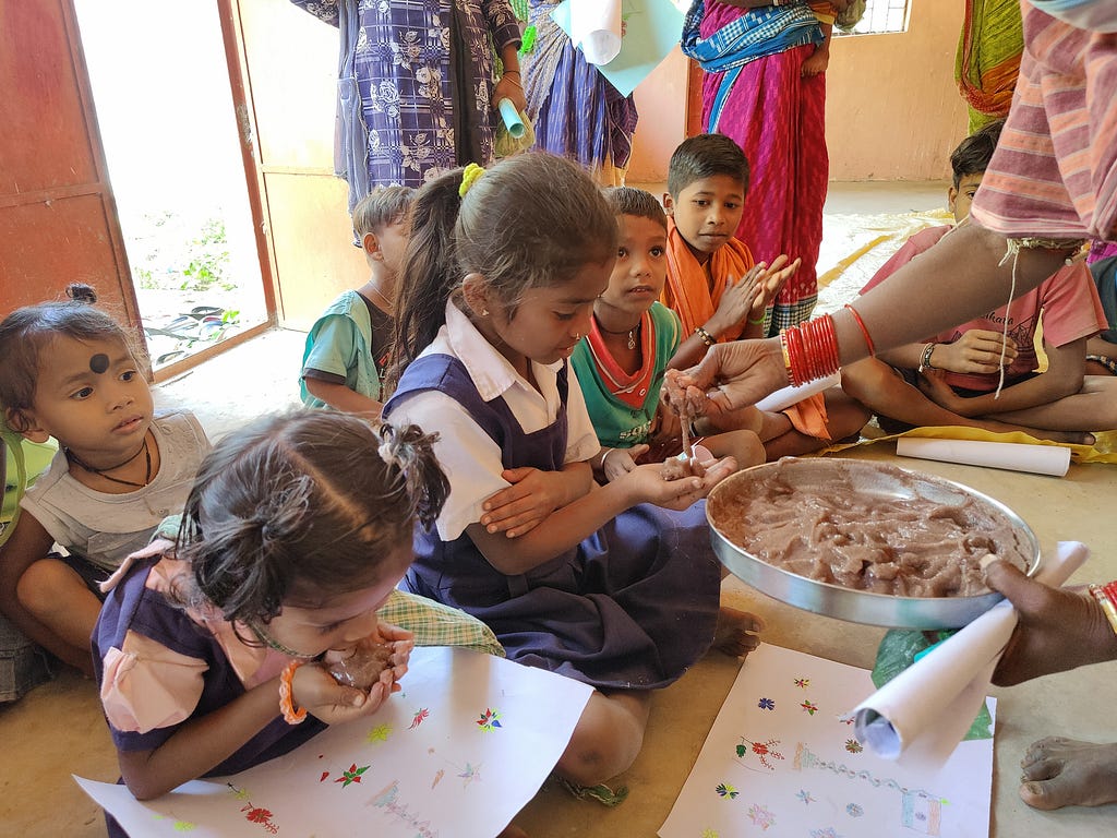 Staff serve millet snacks and keep children engaged with activities while guardians attend capacity building training in Koraput.