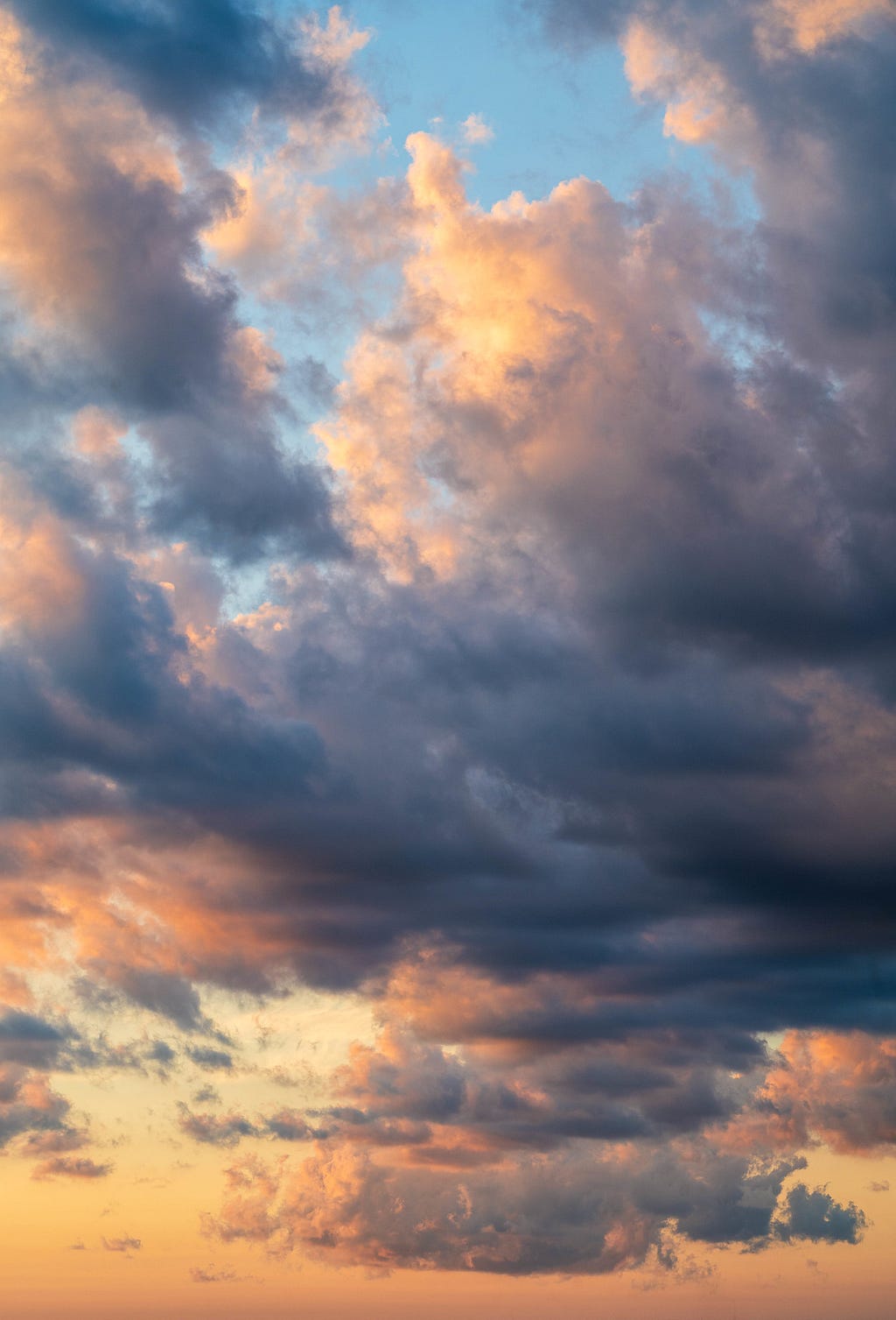 A photo by the author of dramatic clouds with pink-orange highlights and blue-grey shadows over Little Rock, Arkansas.