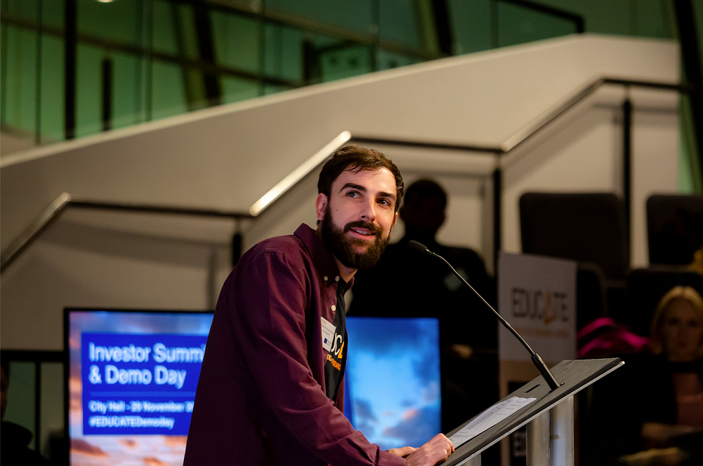 Santiago De Ossorno Garcia at the podium in London’s City Hall Chamber, against a backdrop of EDUCATE Demo Day 2019 branding.