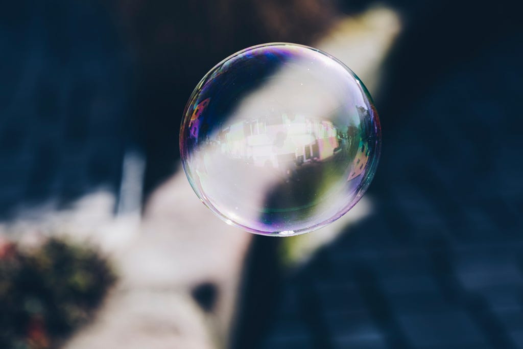 A large single bubble in the foreground of a picture with a blurred background
