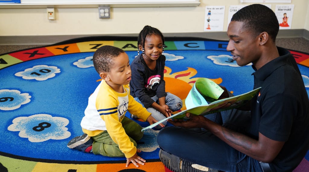 An educator reads a picture book to two children