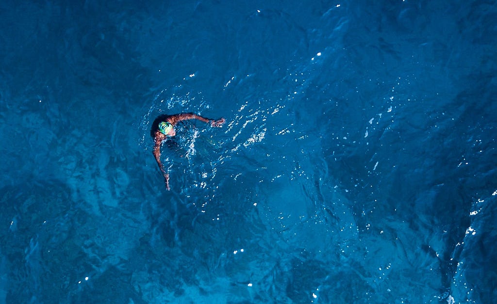 a person swimming in deep blue water