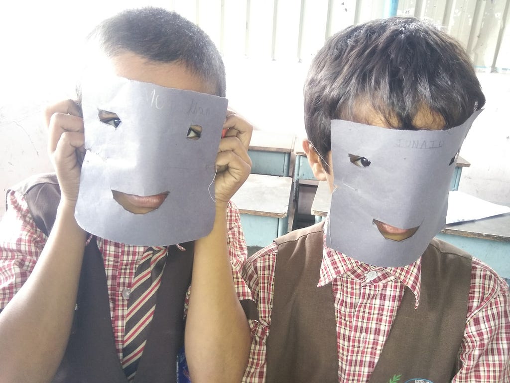 Children holding paper masks up to their faces